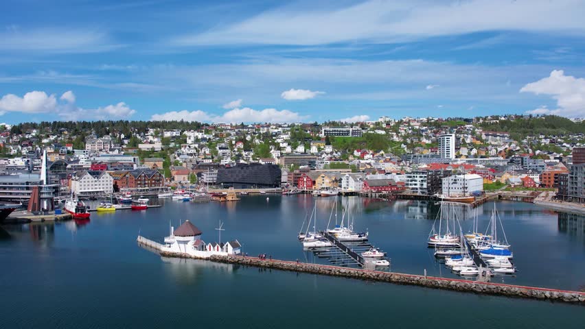 Soaring above the Norwegian city of Troms in the rays of the midnight sun. Picturesque city waterfront, ocean fjord, and a unique blend of urban life and Arctic wilderness. Sea cruises