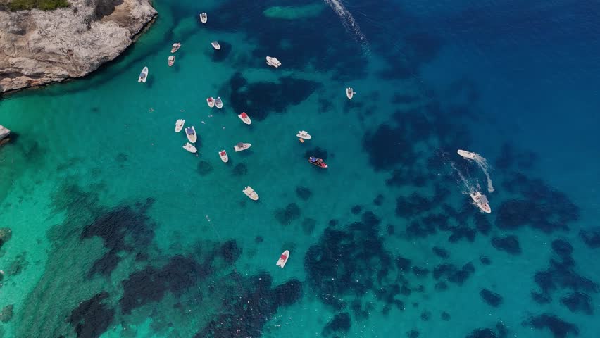 Tourist boats in Cala Mariolu, Sardinia on clear blue waters, aerial view