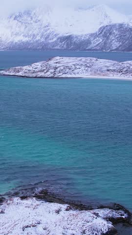 Experience the breathtaking beauty of Sommaroy islands in Troms, Norway during winter. Discover the serene beaches, icy waters, and snow-capped mountains and fishing village.