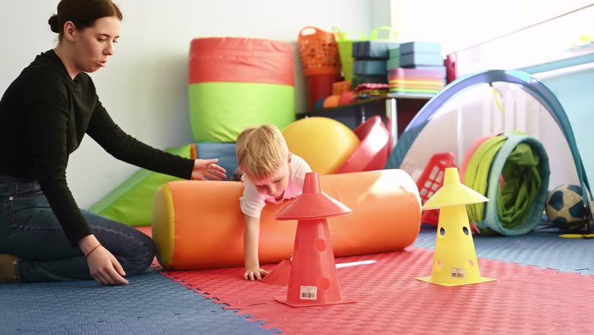 Exercises for motor skills. Preschool child with teacher during developmental activities in a playroom