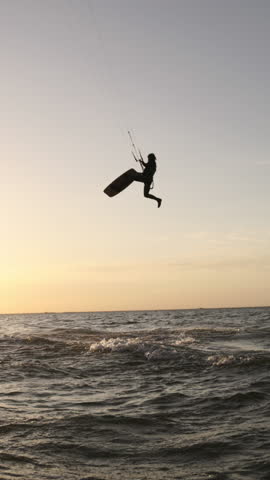 kitesurfer riding wave into sunset slow motion silhouette water splashes golden hour extreme sports adventure
