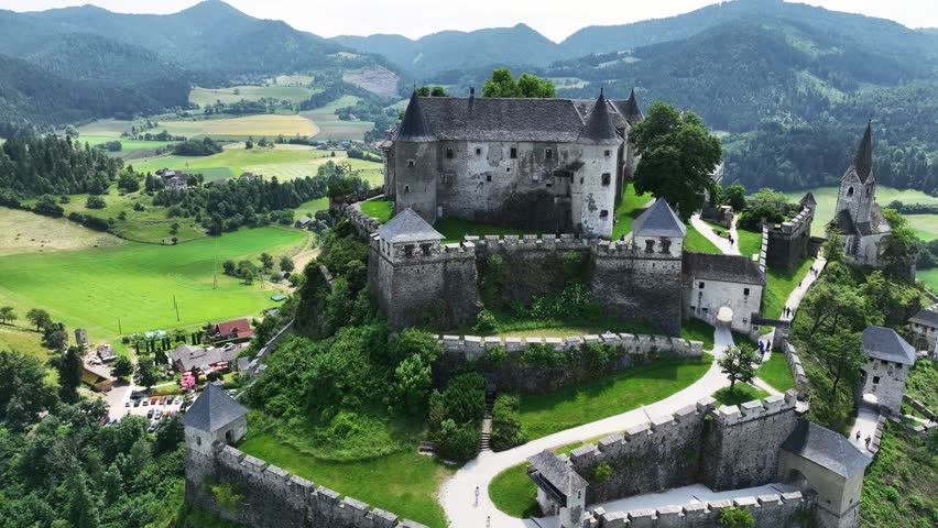 Cinematic drone footage capturing Hochosterwitz Castle on hilltop, fortified walls, dramatic cliffs, summer colors, sweeping aerial movement, historical landmark atmosphere