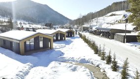Cozy cabins with panoramic windows sit nestled in snowy mountain valley. Frost-covered peaks rise above serene winter scene with crisp air - Powered by Shutterstock - Get 15% off with code: PIKWIZARD15