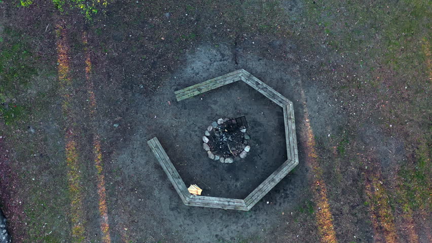 Aerial top-down view of hexagonal bench around fire pit in forested camping area