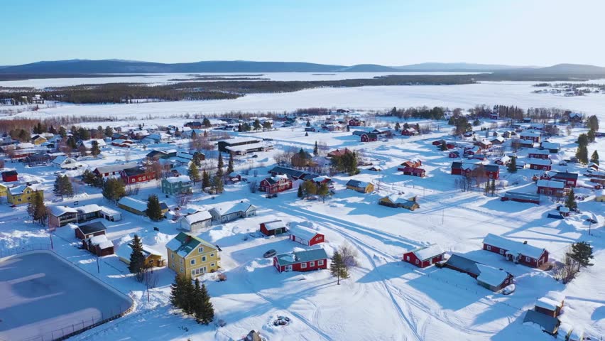 Aerial view of a serene sunset in Myllykoski, Finnish Lapland, showcasing vibrant evening sky colours as the sun sets. This tranquil scene highlights charming buildings, peaceful surroundings, and the breathtaking natural beauty of northern Finland.
