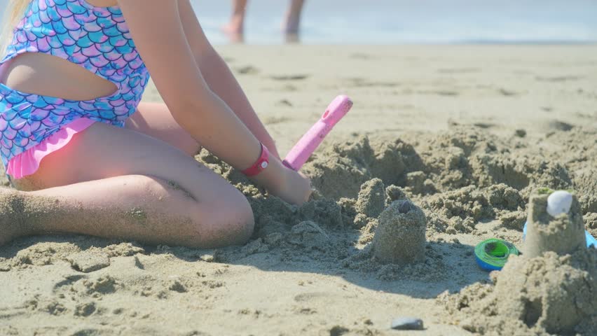 playing with sand near sea, Little girl builds sand castles and forts on beach during summer vacation, enjoying holiday fun, seaside creativity, childhood leisure and joy, relaxed outdoor activity