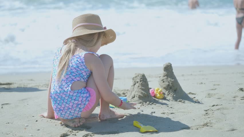 playing with sand near sea, Little girl builds sand castles and forts on beach during summer vacation, enjoying holiday fun, seaside creativity, childhood leisure and joy, relaxed outdoor activity