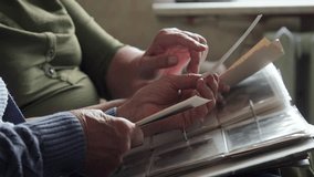 Seniors fondly viewing photographs. Wrinkled fingers gently turning pages of treasured keepsake album. Two aged adults sharing nostalgic moments as they explore their old picture collection together - Powered by Shutterstock - Get 15% off with code: PIKWIZARD15