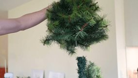 A person decorating a Christmas tree with green branches indoors. Close-up holiday scene with hands arranging pine needles for winter celebration. - Powered by Shutterstock - Get 15% off with code: PIKWIZARD15