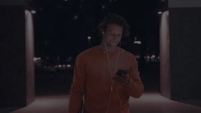 Man walking toward camera in night corridor, tapping phone checking time watching AR clock morphing. Holographic, overlay, futuristic, commuter, urban, neon, projection - Powered by Shutterstock - Get 15% off with code: PIKWIZARD15