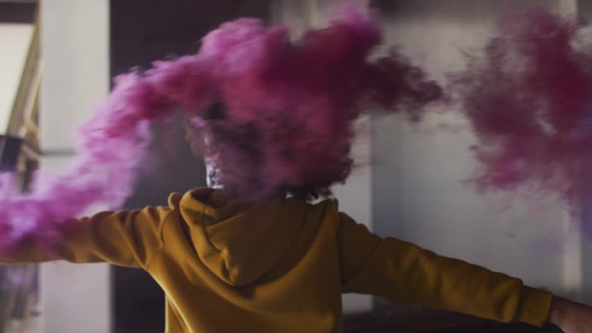 Woman releasing pink smoke from can while spinning in studio, neon Install Now driving app installs. Figure, spin, mist, neon, purple, loft, interior