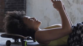 Woman lying on skateboard tapping phone and causing brain HUD forming around head in tech demo. Female, calm, urban, loft, industrial, overlay, neural - Powered by Shutterstock - Get 15% off with code: PIKWIZARD15