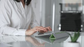 Businesswoman hands using a digital tablet while working at an office glass desk, focused on corporate operations, mobile technology, and data management in a professional workspace - Powered by Shutterstock - Get 15% off with code: PIKWIZARD15
