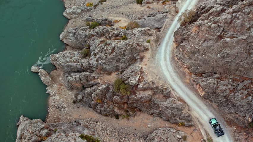 A drives along a winding cliffside road carved into the steep rocky walls of Kemaliye Canyon. The rugged terrain, sharp bends and dramatic orange-toned cliffs form a striking canyon landscape.