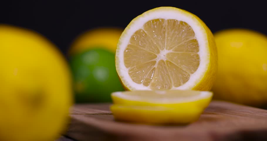 sliced juicy yellow sour lemon lying on the table with limes, sliced ripe citrus fruits lemon and limes are lying on a wooden table