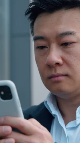 Asian middle-aged business man with mobile phone unhappy Japanese businessman annoyed using smartphone Korean Chinese male stressed sad with low battery cellphone problem in city reading bad news