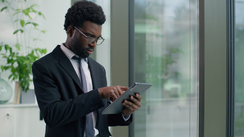 Concentrated focused African American businessman in office using digital tablet analyze data project with wireless computer technology business man guy male employer working online internet task - Powered by Shutterstock - Get 15% off with code: PIKWIZARD15