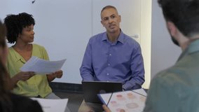 Coworkers reviewing charts and exchanging ideas in a relaxed office meeting. Multicultural professionals collaborating on strategies in a modern creative workspace. Teamwork and innovation concept. - Powered by Shutterstock - Get 15% off with code: PIKWIZARD15