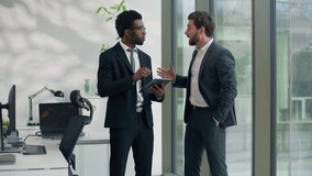 Two multiracial businessmen emotional discussing startup in office holding at digital tablet business men diverse male colleagues talking cooperation teamwork corporate friendship sharing news ideas - Powered by Shutterstock - Get 15% off with code: PIKWIZARD15