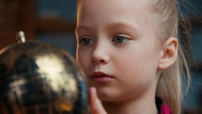 Close up little Caucasian child kid girl daughter rotating gold globe studying at evening home baby exploring world search countries dreaming traveling study geography planet cartography navigation - Powered by Shutterstock - Get 15% off with code: PIKWIZARD15