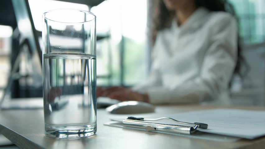 Close-up glass of still water business woman putting pill remedy painkiller inside at office unrecognizable businesswoman female girl worker ill sick manager with computer work preparing vitamin drink