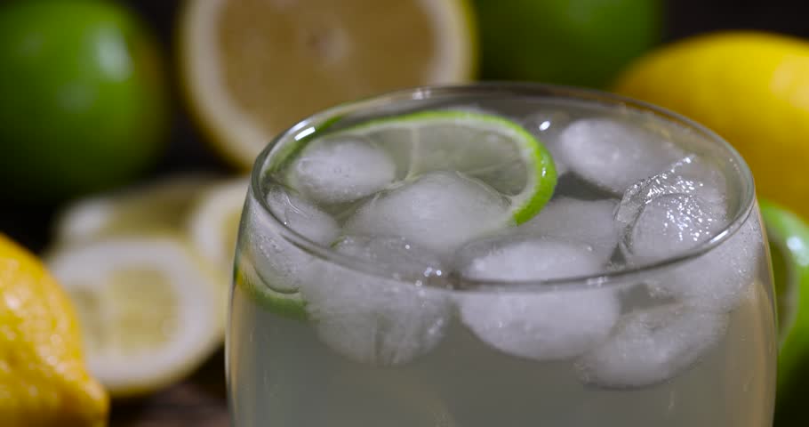 cold lemon drink with the addition of pieces of pure ice in a glass, sweet and sour refreshing drink with lemon flavor and whole juicy limes