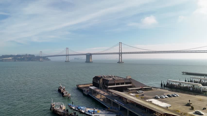 A steady aerial drone shot hovering above the Port of San Francisco along the Embarcadero. The footage captures the waterfront buildings, piers, Ferry Building area, and surrounding urban activity fro