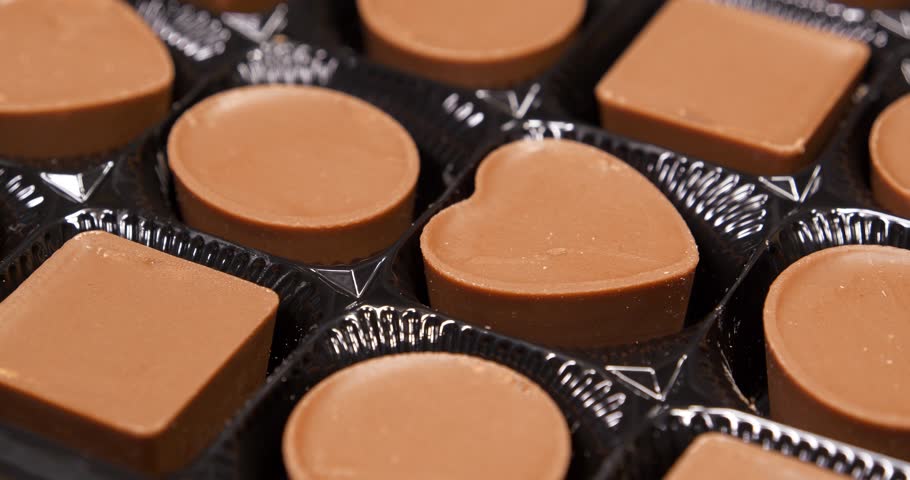 Valentines Day Gift. Candies are round, square and heart-shaped. Chocolate candies in a packaging. Delicious chocolate candy with of different forms, including heart-shaped ones