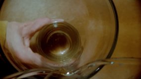 Top down perspective shows a hand holding a glass while an amber colored, fizzy beverage is poured inside in mesmerizing slow motion, creating bubbles and swirls - Powered by Shutterstock - Get 15% off with code: PIKWIZARD15