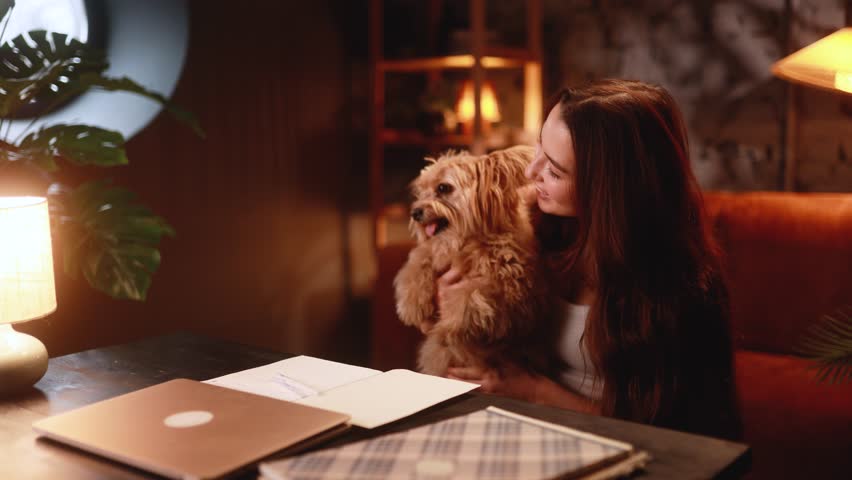 nurturing moment between woman and small dog, relaxed home scene with affectionate dog and owner, comfortable domestic setting emphasizing close relationship with beloved small canine friend