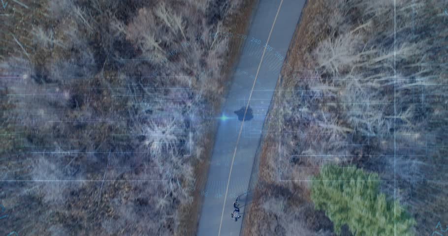Drone tracking rider, teen riding bike on yellow centerline, grid flare tracing route for leisure. Cyclist, forest, aerial, trail, paved, helmet, overcast