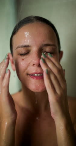 A girl takes a shower, washing her hair and playfully interacting with water. Her joyful expressions and candid moments showcase a refreshing experience in a serene setting.