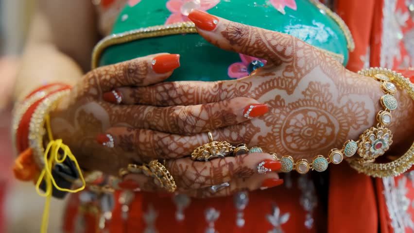 Close-up of traditional Indian wedding hand adornments, showcasing henna, bangles, jewelry, and cultural bridal decorations.