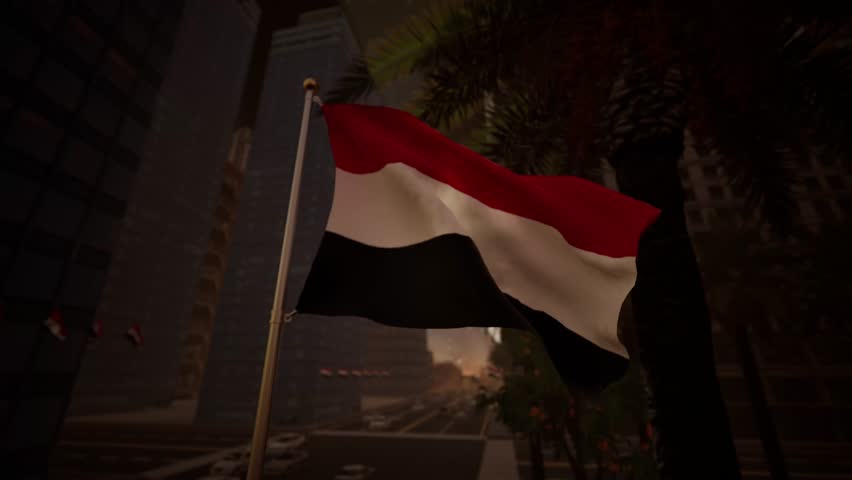 Yemen national flag waving at sunset with warm golden light reflecting across buildings, palm trees and city streets in an urban setting. As the sun begins its descent over the coastal city of Aden, the red, white and black colors of the Republic glow with an amber hue. The fabric captures the fading daylight, creating a dramatic silhouette against the deepening tones of the evening sky. This moment is poignant, often associated with the close of Revolution Day commemorations, where the emblem stands as a testament to history. The tricolor banner ripples gently in the cooling seaside breeze, its motion slower and more graceful than during the heat of the day. Background structures, perhaps including the Crater district or modern hotels, are bathed in a soft, orange radiance that highlights their contours. Shadows stretch long across the boulevard, adding cinematic depth and contrast to the visual narrative. The textile material appears rich and velvety, with the white band reflecting the last rays of sunshine. Nearby palms sway lazily, framing the ensign in a tropical context typical of the southern governorates. Traffic lights begin to twinkle in the distance, signaling the transition from day to dusk in this busy Arabian metropolis. The fluttering pendant serves as a powerful symbol of identity in the Middle East, evoking feelings of nostalgia and hope. Clouds on the horizon turn shades of violet and pink, providing a stunning canvas for the national jack. This footage perfectly encapsulates the peaceful yet vibrant atmosphere of a Yemeni evening, suitable for productions requiring emotive or inspirational imagery. The standard remains aloft, a steadfast marker of territory and pride as the city prepares for the night. Every wave of the cloth reflects the golden hour's beauty.