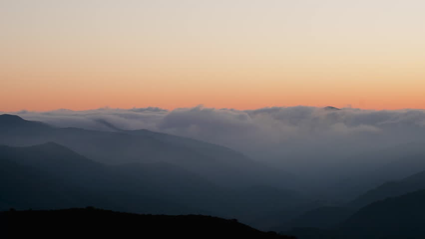 Panning Across a Cloudy Mountain Range Under Sunset Skies