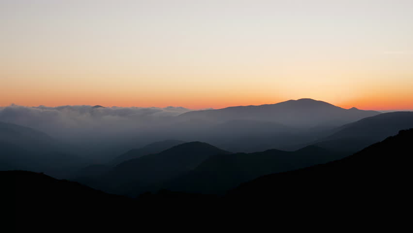 Panning Across a Cloudy Mountain Range Under Sunset Skies