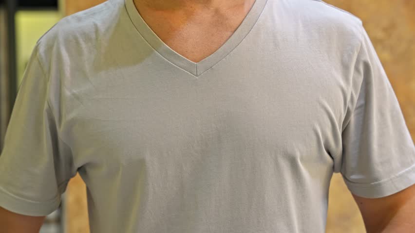 Closeup view of a man striking his chest with both fists. Strong rhythmic motion focused on the torso without showing the head.