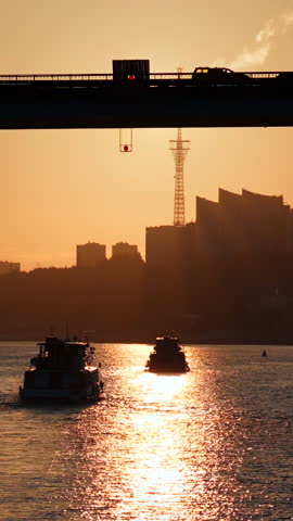 Passenger ferry crossing river at sunset under bridge. Clip