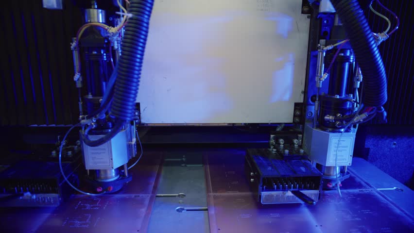 Automated laser cutter precisely cuts a metal sheet, illuminated by intense blue light, showcasing advanced manufacturing technology in a modern factory setting