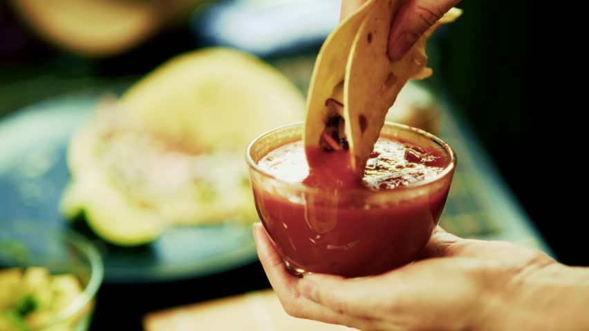 Dipping Taco Into Red Salsa Sauce, Authentic Mexican Food Preparation. Savory Dip Taco And Corn Tortilla, Traditional Hispanic Cuisine. Party Food And Appetizer. Spicy Salsa Dip. Making Tacos Mexican