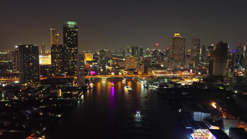 Aerial view of illuminated skyscrapers in Bangkok city and Chao Phraya River in night time, 4k
