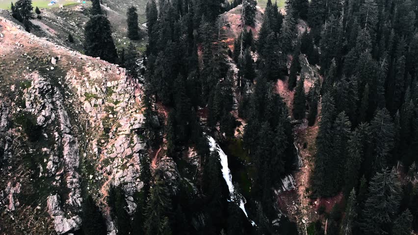 Powerful Waterfall Flowing Through Dark Forest Canyon
