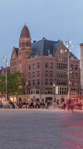 The Dam square in Amsterdam day to night transition timelapse, The Netherlands. The place is the historical center of the city and includes monument, museum, shops and hotels