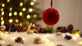 A red Christmas ornament hangs elegantly with blurred festive lights and pine cone decor in the background. - Powered by Shutterstock - Get 15% off with code: PIKWIZARD15