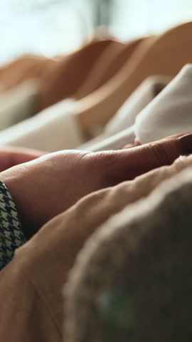 Clothes rack, hands and shopping with person in boutique for decision or selection of material. Clothing, fashion and retail with customer in store for choice or purchase of fabric and textile