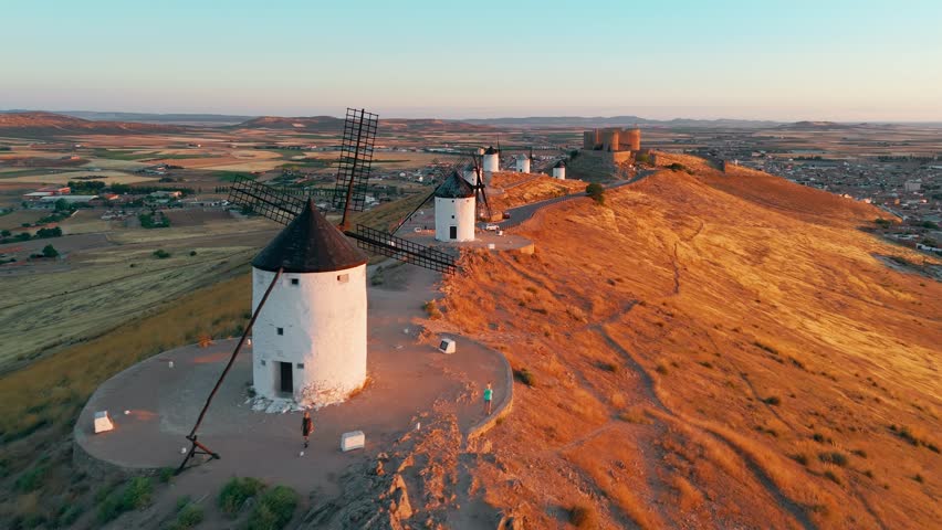 Aerial view of the historic windmills of Consuegra at sunrise, Castilla-La Mancha, Spain. Old historic windmills of Don Quixote character on the hills in morning light. Molinos de Viento de Consuegra