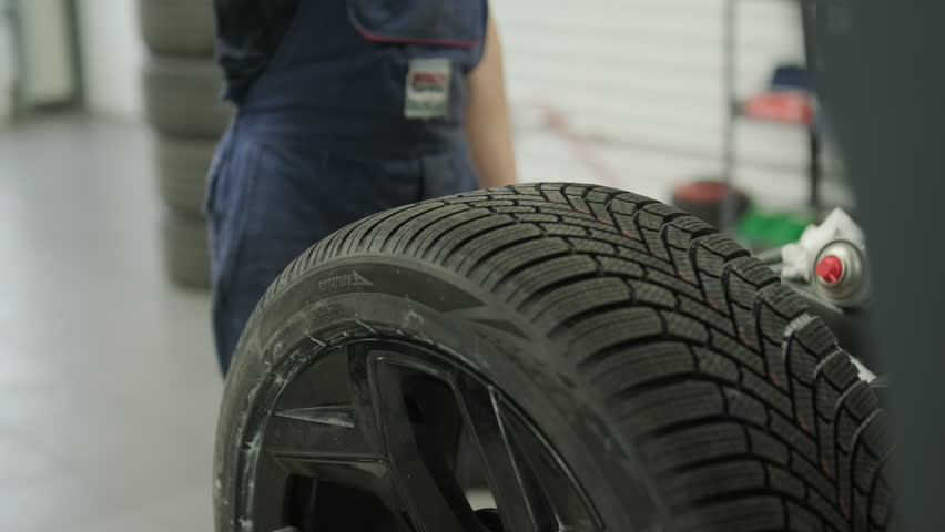Professional auto mechanic changing and balancing car wheel in a tire fitting workshop