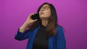 Hispanic woman in blue blazer tilts head in side profile while holding smartphone to ear in studio; concentration. - Powered by Shutterstock - Get 15% off with code: PIKWIZARD15
