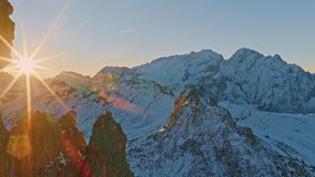 Cinematic aerial drone view of the snowy Dolomites in Val Gardena at sunrise. Sun rays create dramatic lens flares over rugged winter peaks and rocky ridges. A stunning panoramic mountain landscape id - Powered by Shutterstock - Get 15% off with code: PIKWIZARD15
