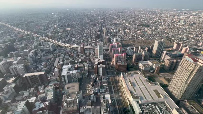Wide aerial high angle shot of Osaka downtown in the morning, dense skyline of office towers and apartment buildings under clear sky, modern Japanese business cityscape and urban landscape background